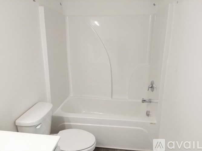 A white toilet sits next to a white bathtub in a bathroom.