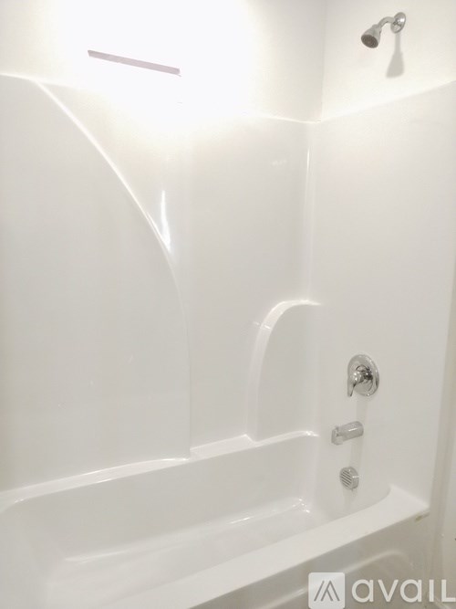 A white bathtub with a shower head and faucet.