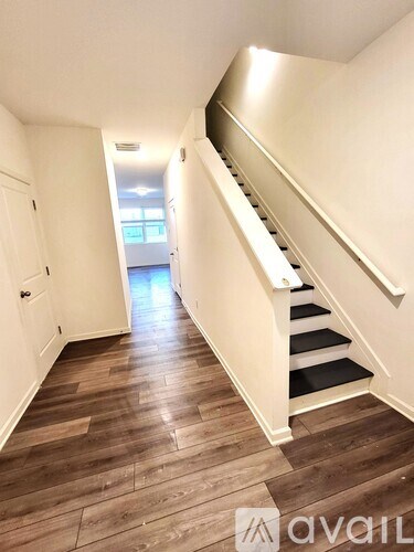 A hallway with wooden floors and a staircase.