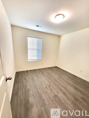 A room with wooden flooring and a window with blinds.
