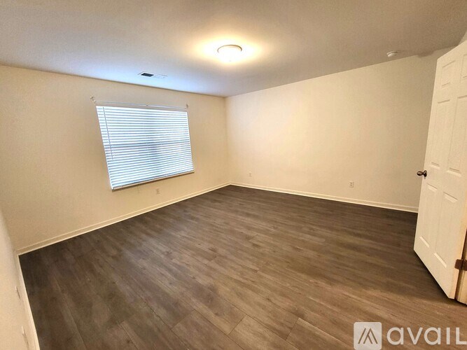 A room with wooden flooring and a window with blinds.