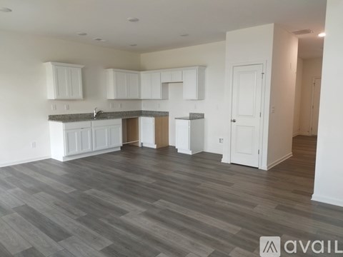 A spacious kitchen with white cabinets and a wooden island.