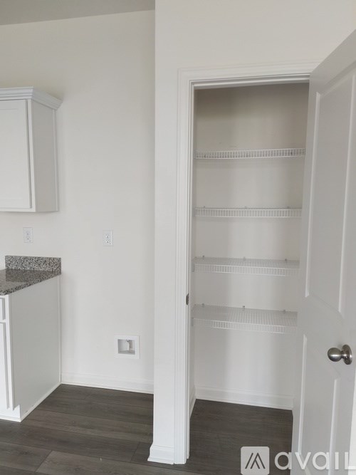 A white pantry with a door open to a hallway.