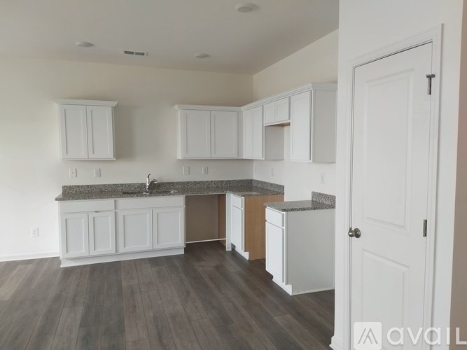 A kitchen with white cabinets and a wooden floor.