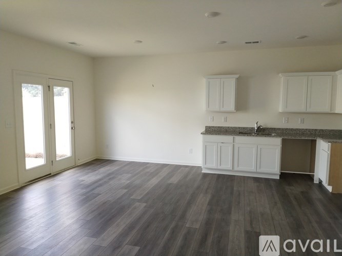 A spacious room with wood flooring and white cabinetry is available for rent or purchase.