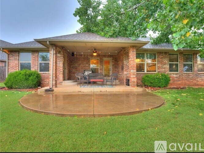 A house with a brick exterior and a patio with a table and chairs.