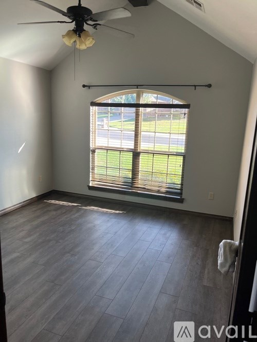 A room with a ceiling fan and a window overlooking a street.