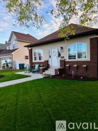 A house with a white door and windows is surrounded by a green lawn.