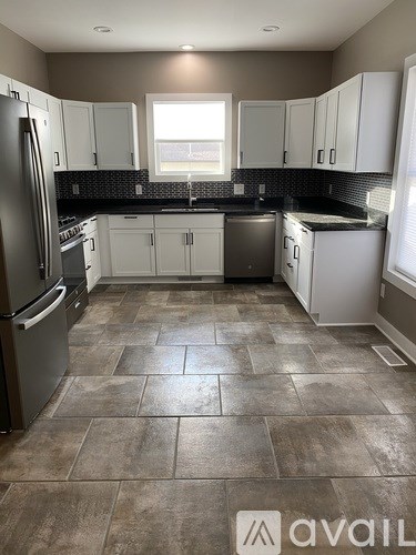 A kitchen with tile flooring and a refrigerator.