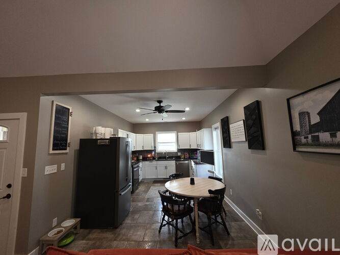 A kitchen with a black fridge and a dining table with chairs.