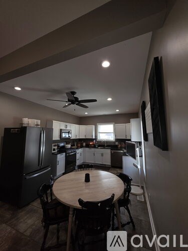 A kitchen with a table and chairs in the foreground and a refrigerator in the background.