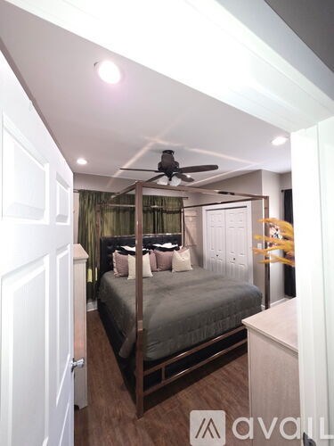 A bedroom with a bed, dresser, and ceiling fan.