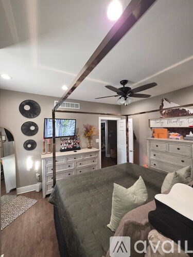 A bedroom with a bed, dresser, and ceiling fan.
