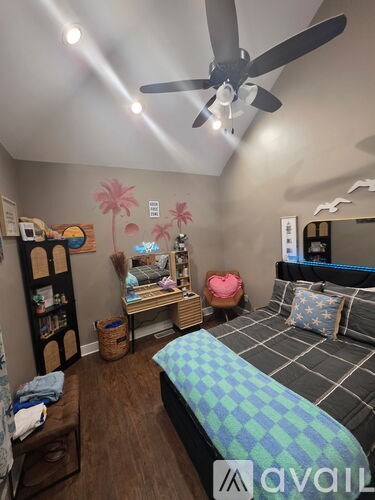 A bedroom with a bed, a bookshelf, and a ceiling fan.