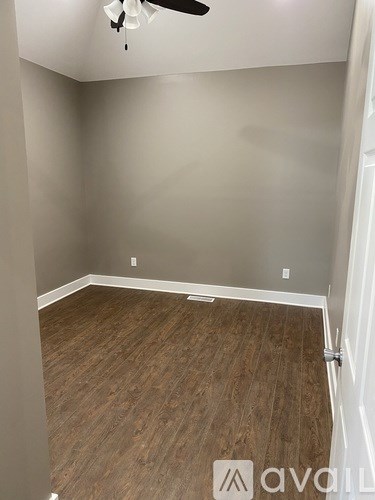 A room with wooden flooring and a ceiling fan.