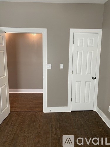 A room with a white door and a brown floor.
