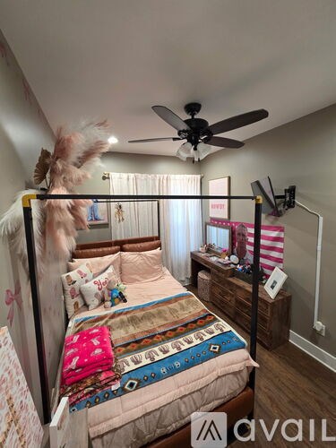 A bedroom with a bed, a ceiling fan, and a wall-mounted TV.