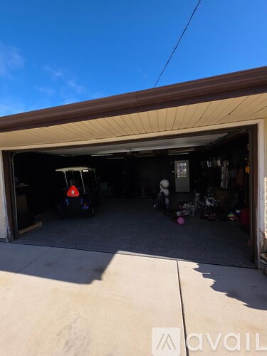 A car is parked in a garage with a golf cart.