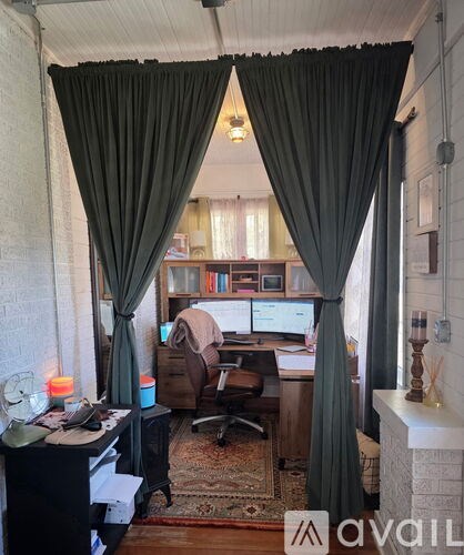 A room with a desk, chair, and computer monitors.