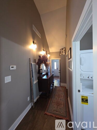 A hallway with a rug and a door on the right.
