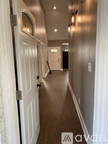 A hallway with a white door and a black handle.