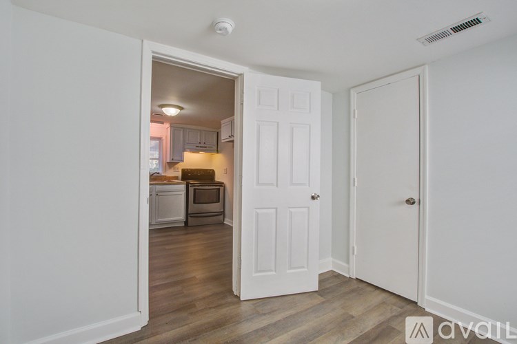 A kitchen is visible through an open door in a white room.