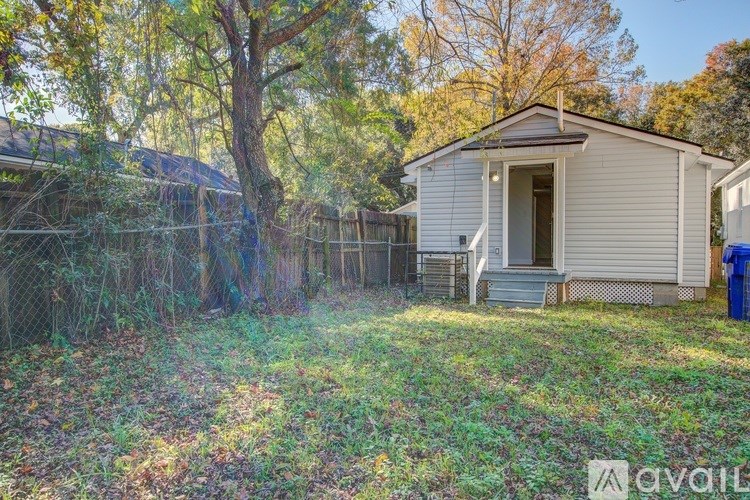A small house with a fence and trees in the background.