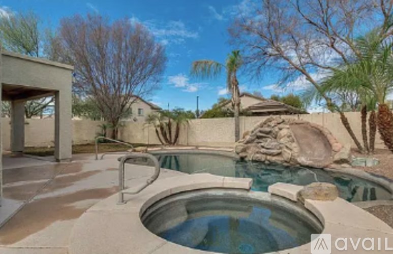A pool with a hot tub in the middle of a backyard.