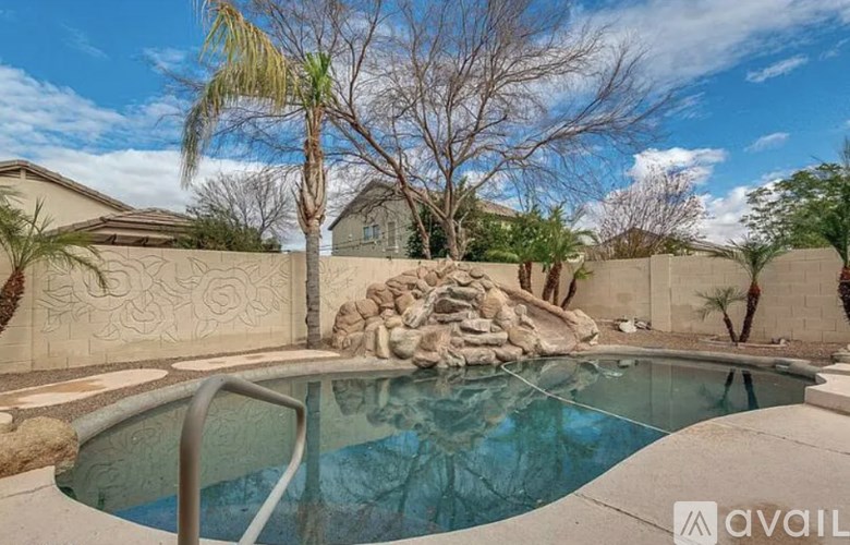 A pool surrounded by a wall with a statue and trees.