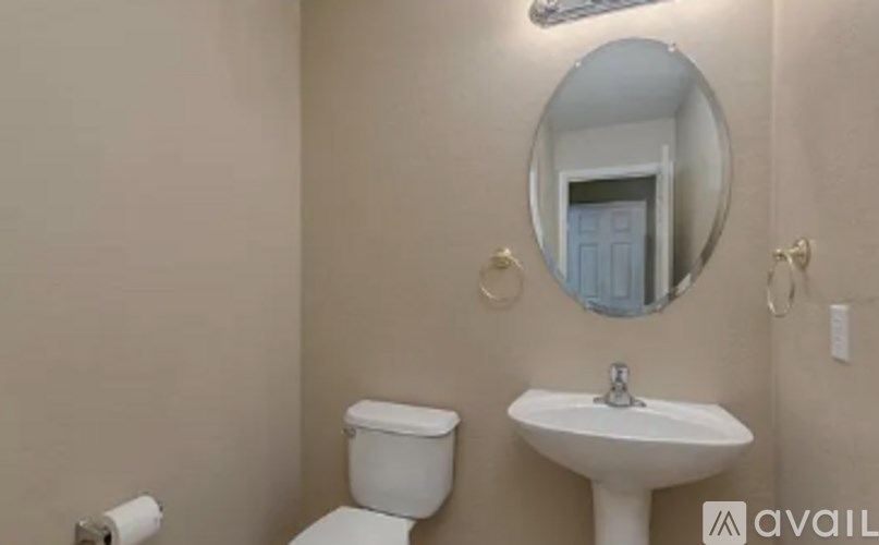 A bathroom with a toilet, sink, and mirror.