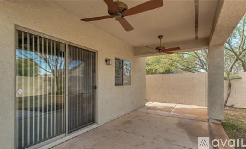 A patio with a ceiling fan and a wall-mounted fan.