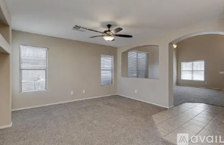 A spacious room with a ceiling fan and three windows.
