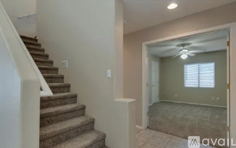 A staircase leads up to a landing with a window and a fan.