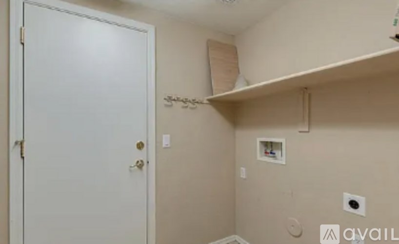 A white door is on the left of a wall with a shelf and a small white box on it.