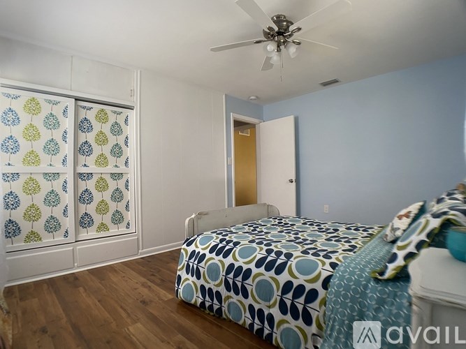 A bedroom with a bed, a ceiling fan, and a window with a curtain.