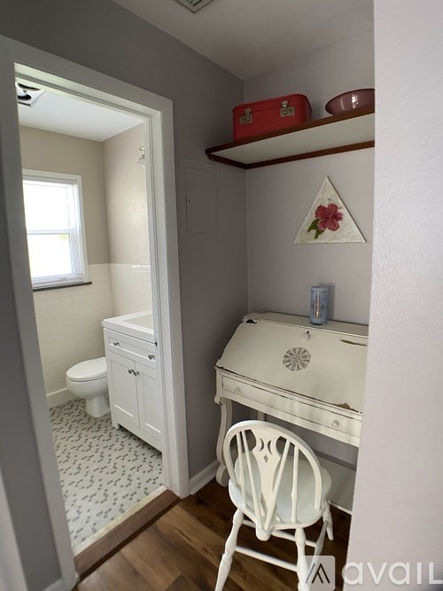 A small white bathroom with a toilet, sink and a chair.