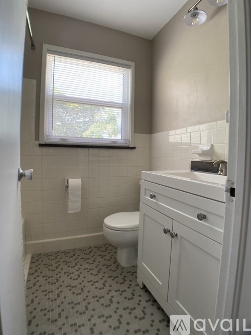 A bathroom with a toilet, sink, and a window.