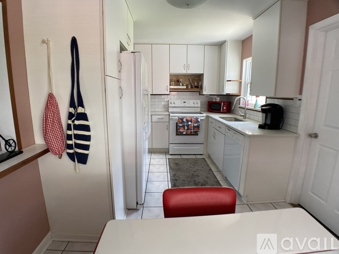 A kitchen with white appliances and a red chair.