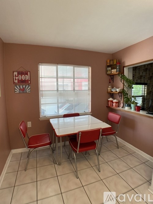 A dining room with a white table and red chairs.