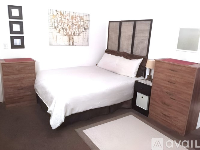 A bedroom with a bed, nightstand, and a painting on the wall.