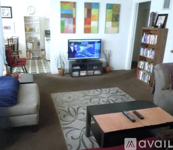 A living room with a television, a sofa, a coffee table, and a bookshelf.