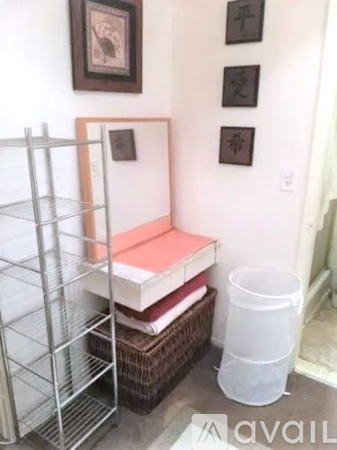 A white plastic container is on the floor next to a shelf with several books stacked on top of it.