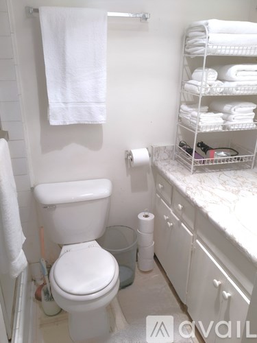 A white toilet with a white towel hanging on the wall.