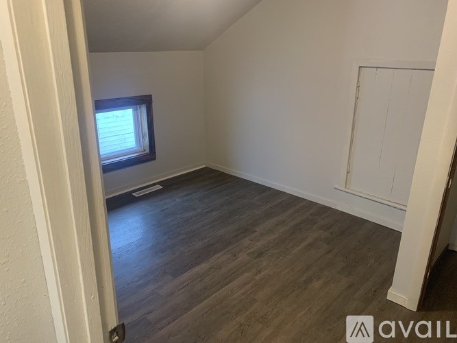 A room with wooden flooring and a window.