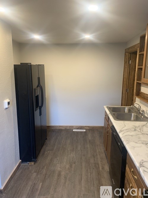 A kitchen with a black fridge and wooden cabinets.