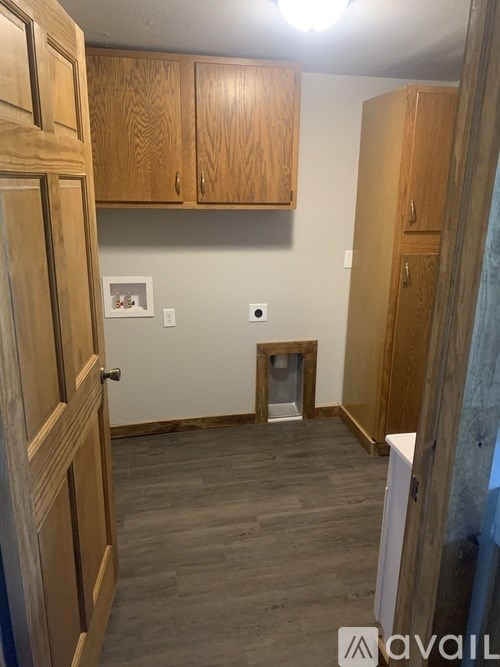 A room with wooden cabinets and a small doorway leading to a bathroom.