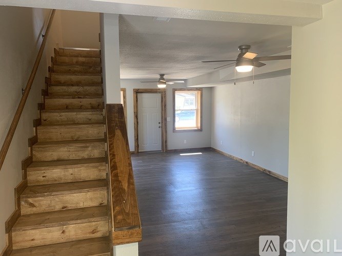 A room with wooden stairs and a ceiling fan.
