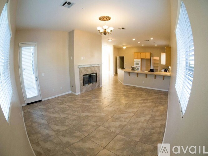 A living room with a fireplace and a kitchen area in the background.