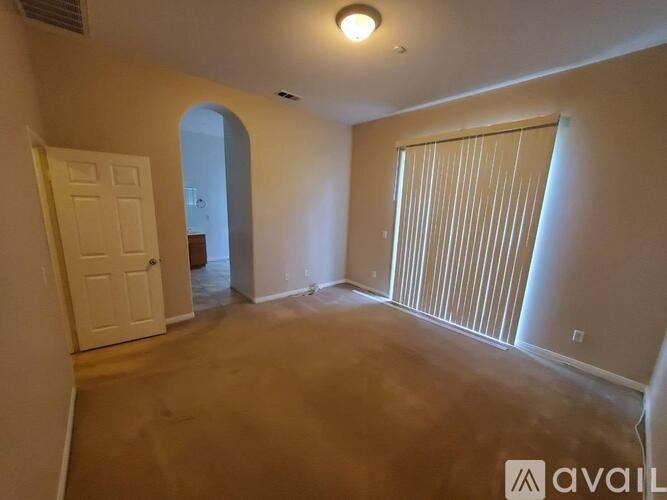 A room with a door and a window with blinds.