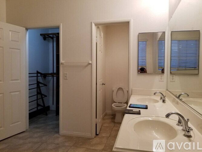 A bathroom with a toilet, sink, mirror and a door.